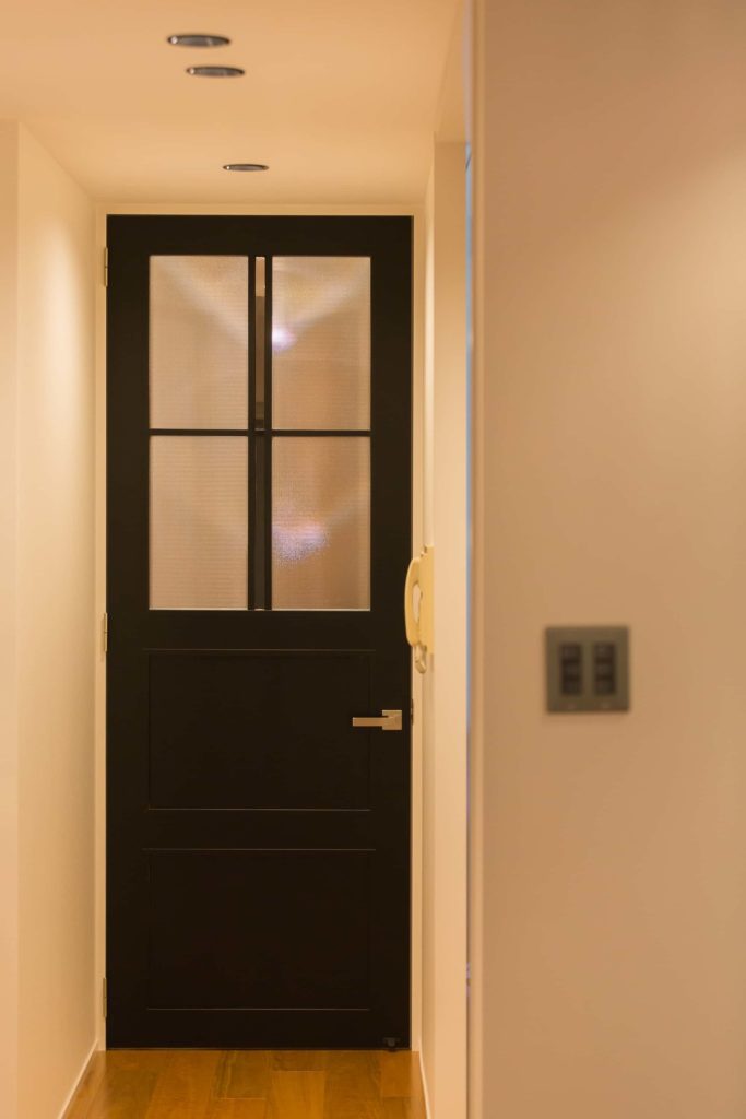 ブラックに塗装された背高のドア。両サイドの模様ガラスに対して中央だけクリアガラスを用いてます。