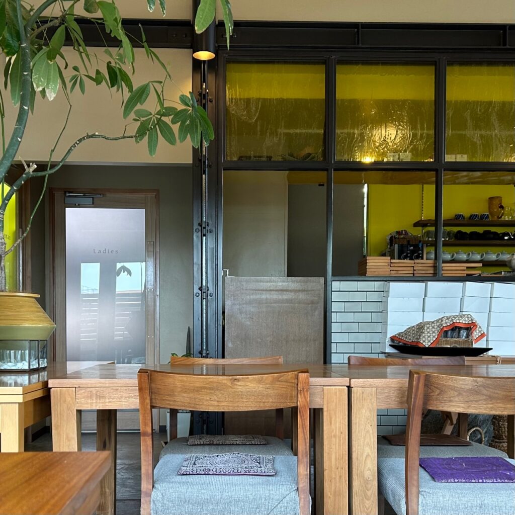 座り心地の良い木の椅子と厨房の色ガラスと植物を眺めるカフェ時間