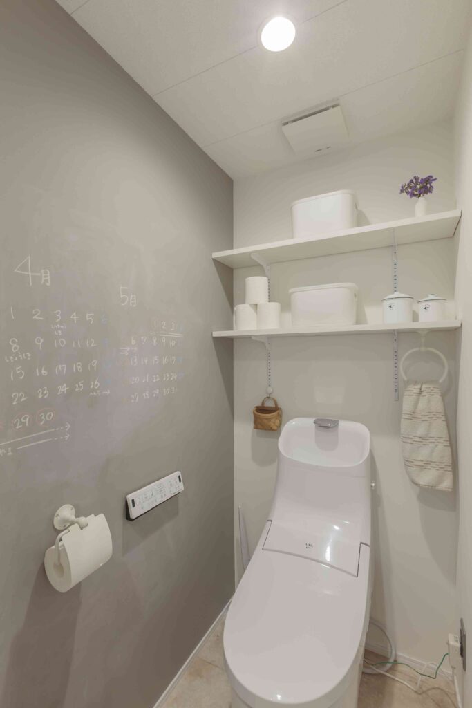 豊橋市でリノベーションを手掛けるリノクラフト株式会社が設計施工したI様邸のトイレの事例写真です。アクセサリーと背面の収納棚は白ですっきりまとめられています。チョークで書けるアクセントクロスはサンゲツのものです。